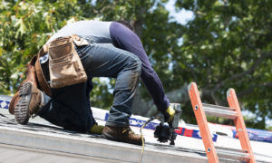 A roofer works to install shingles on a residential home.