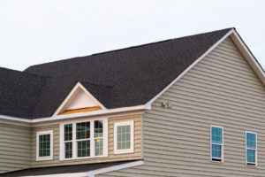 A single-family home has beige vinyl siding and a new, black shingle roof.