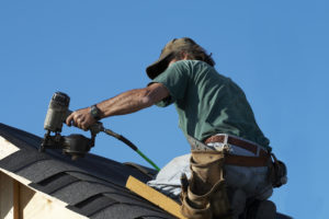 A roofer working on a shingle roof