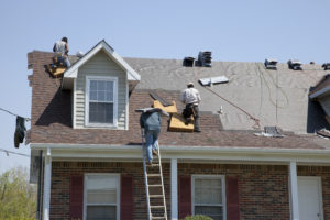 Roofers replacing damaged shingles after storm with very high winds came through over night