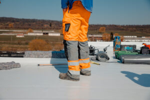 Roofer man works on a flat roof with pvc membrane insulation system