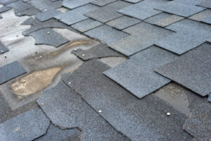 lose Up View Of Bitumen Shingles Roof Damage That Needs Repair.