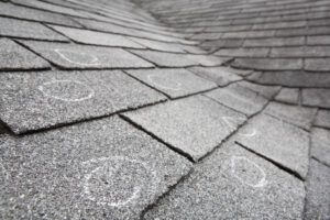 Chalk circles marking damage on a shingle roof